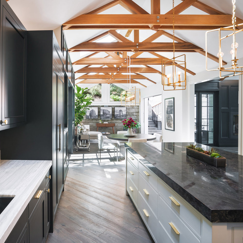 Cascade Canyon custom new home in Mill Valley featuring modern farmhouse design with exposed wood beam ceilings, open-concept kitchen with black and white cabinetry, brass fixtures, outdoor living spaces, and a separate guesthouse, all nestled among mature redwood trees in Marin County