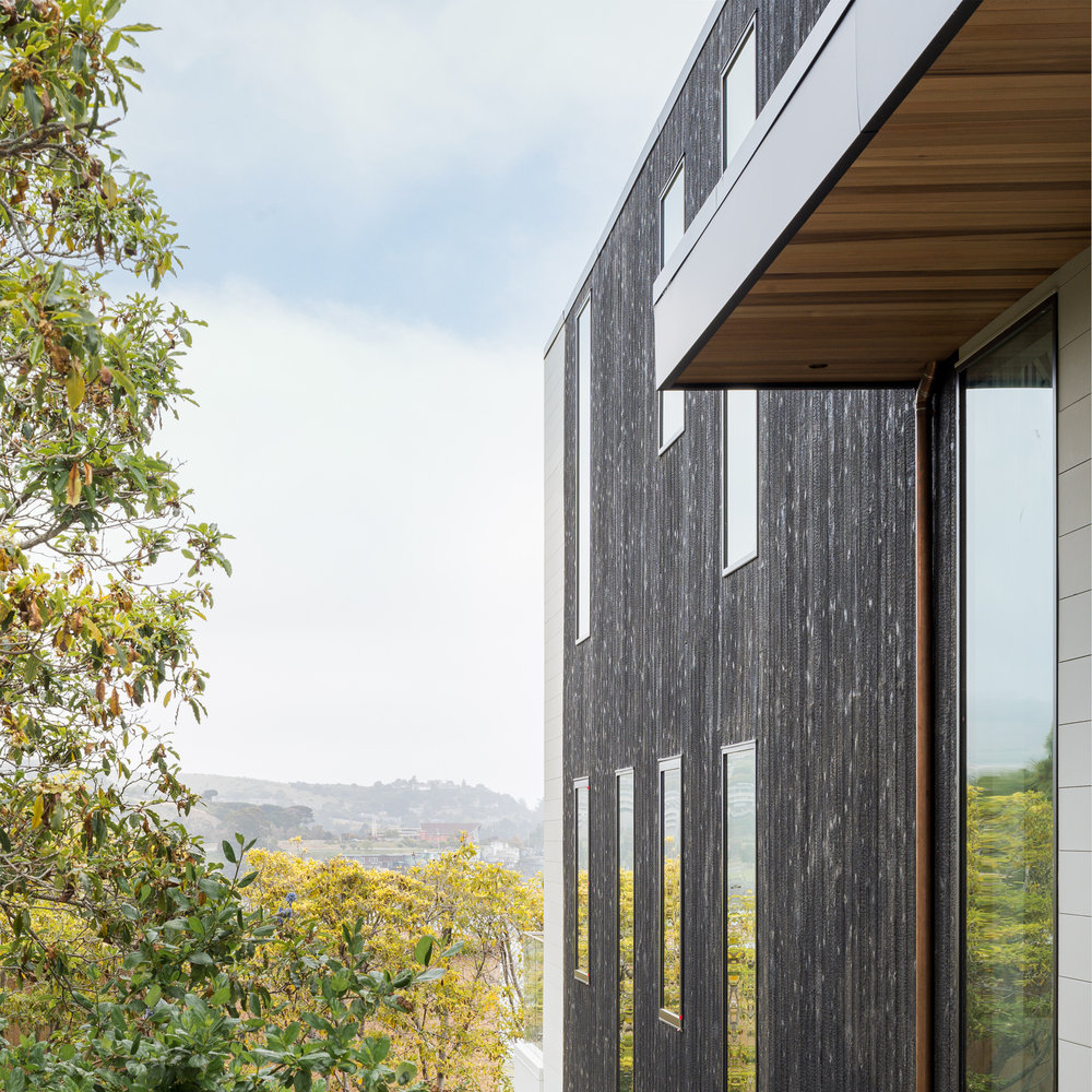 Strawberry Residence – Modern Mill Valley home featuring charred wood siding, horizontal wood louvers, and expansive bay views with indoor-outdoor living spaces